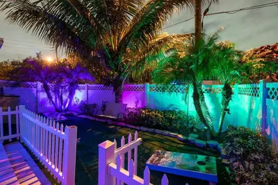 a backyard with a white fence and a pond with palm trees at ~Villa Victoria Luxury! (Pool)~1 mile from beach in Fort Lauderdale
