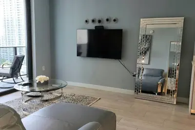 a living room with a tv and a glass table at Gorgeous Upscale Condo in the Middle of Brickell in Miami