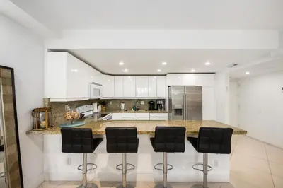 a kitchen with a counter with black stools at 2-Bedroom Beach Condo in Sunny Isles in Miami Beach