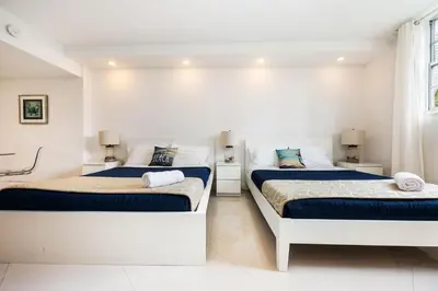 two beds in a room with white walls at 2-Bedroom Beach Condo in Sunny Isles in Miami Beach