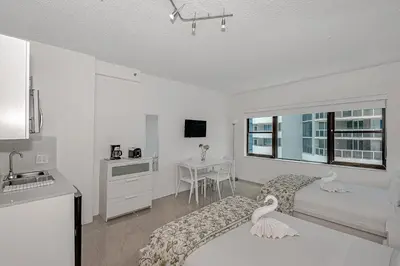 a white room with a bed and a kitchen at Beach Front Studio Miami Beach in Miami Beach