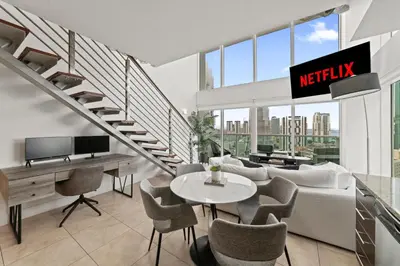 a living room with a couch and a table and chairs at Skyline Serenity - Brickell On The River - Bi-Level Loft with Breathtaking Views On The Ocean in Miami