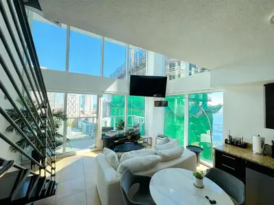 a living room with white furniture and large windows at Skyline Serenity - Brickell On The River - Bi-Level Loft with Breathtaking Views On The Ocean in Miami
