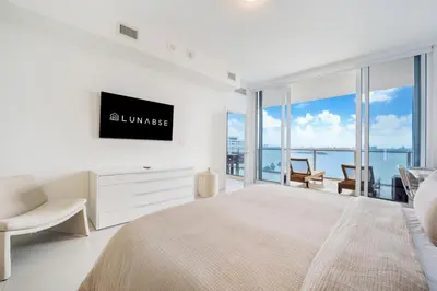 a white bedroom with a large bed and a tv at Lunabase Waterfront Paradise in Miami