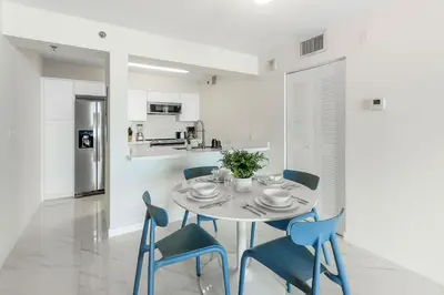 a white dining room with a table and blue chairs at Brickell Bay View Oasis with Pool Hot Tub and Gym in Miami