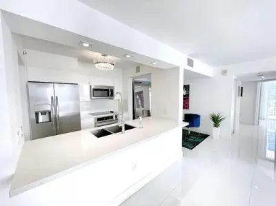 a white kitchen with a stainless steel refrigerator at Luxury Sky Villa with City and Ocean Views in Miami