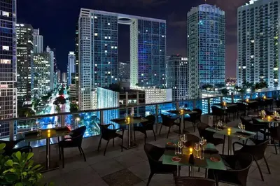 a restaurant with tables and chairs on a rooftop at night at Blissful Sky Residence with Ocean and City Views in Miami
