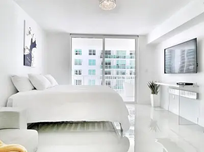 a white bedroom with a large bed and a tv at Blissful Sky Residence with Ocean and City Views in Miami