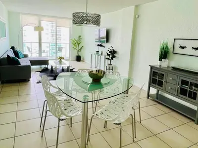 a living room with a glass table and white chairs at Oceanview Beachfront Condo on Tides Resort in Hollywood