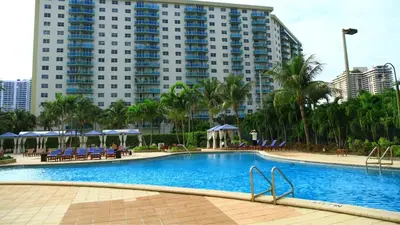 a swimming pool in front of a large building at Family Beach Home w Ocean & Bay Views - Upgraded Corner Unit in Miami Beach