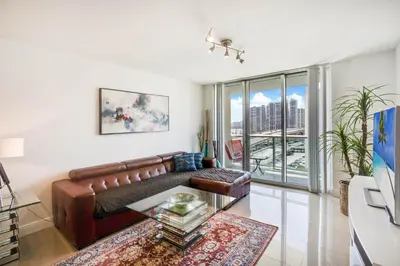 a living room with a leather couch and a large window at ⌘Family Beach Home w Amazing Water Views - Upgraded Unit ⌘ in Miami Beach