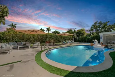 a swimming pool in a yard with chairs and umbrellas at Miami Paradise - Htd Pool, Mini Golf, Playground, BBQ, Arcade Machine, baby items in Miami