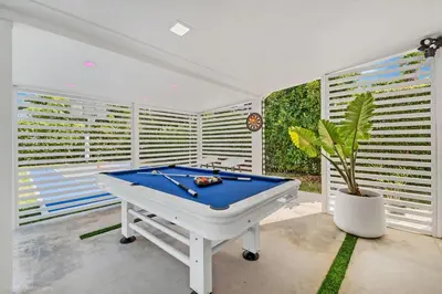 a pool table in a room with windows at Miami Paradise - Htd Pool, Mini Golf, Playground, BBQ, Arcade Machine, baby items in Miami