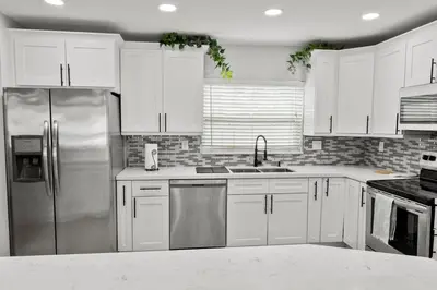 a kitchen with white cabinets and a stainless steel refrigerator at Stadium Sunflower Miramar home, 3 bd, 2 ba in Miramar