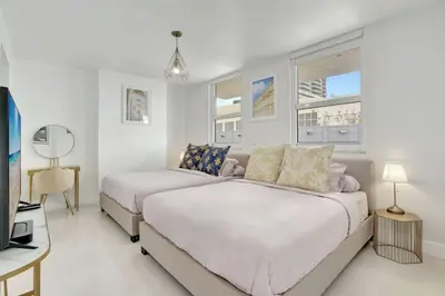 a bedroom with two beds and a desk and windows at 3BR Penthouse with European Flair n Amazing Views in Miami