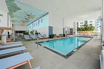 a pool in a hotel lobby with chairs and tables at Explore Miami's Heat - Cozy Studio POOL & GYM in Miami