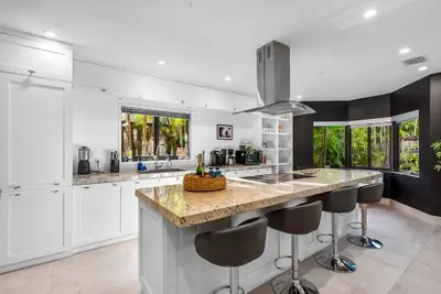 a kitchen with white cabinets and a island with bar stools at Coconut Grove Villa with heated Pool sleeps 12 in Miami