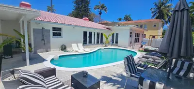 a swimming pool with chairs and a house at Beachside Bliss Pool Retreat Half mile to Beach in Hollywood