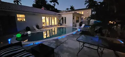 a swimming pool in front of a house at night at Beachside Bliss Pool Retreat Half mile to Beach in Hollywood