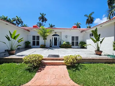 a white house with palm trees in the yard at Beachside Bliss Pool Retreat Half mile to Beach in Hollywood