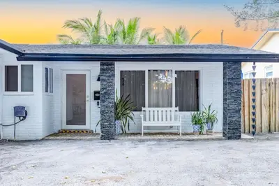 a white house with a bench on the front porch at Casa Tropicana - Heated Pool, Game Room & Mins from beach in Hallandale Beach