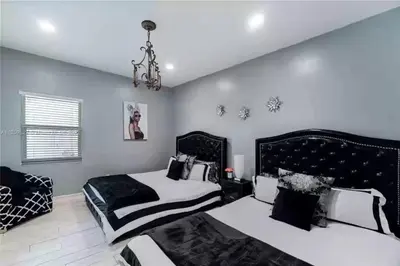 a bedroom with two beds and a chandelier at Pool Paradise Half mile to Beach w Massive Yard! in Hollywood