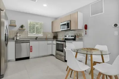 a kitchen with white appliances and a table and chairs at Sistrunk Shades Entire Compound 5 Homes 50 Guests in Fort Lauderdale