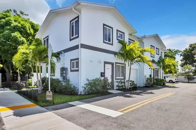 a white building with palm trees in front of it at Sistrunk Shades Entire Compound 5 Homes 50 Guests in Fort Lauderdale