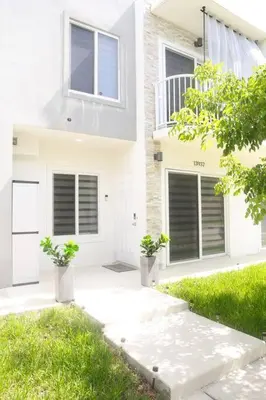 a white house with two potted plants in front of it at Insta Worthy Modern Bungalow in Homestead