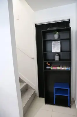 a black book shelf with a blue stool in a hallway at Insta Worthy Modern Bungalow in Homestead