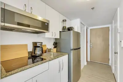 a kitchen with white cabinets and a stainless steel refrigerator at Glam Studio: Sleeps 4 x Pool x Gym x Parking in Miami