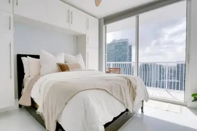 a white bedroom with a large bed and a large window at Chic Penthouse: 3BR x Pool x Gym x 2 Parking Spots in Miami