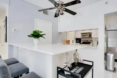 a white kitchen with a ceiling fan and a counter at Chic Penthouse: 3BR x Pool x Gym x 2 Parking Spots in Miami