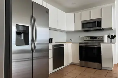 a kitchen with white cabinets and a stainless steel refrigerator at Pavilion - Best ocean sunrise-Miami Beach in Miami Beach