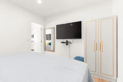 a white bedroom with a bed and a flat screen tv at 316 Footloose #3 in Hollywood