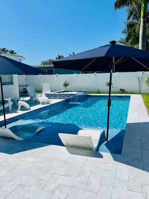 a swimming pool with a blue umbrella and some chairs and sidx sidx sidx at Designer Pool & Family Dream Home in Hollywood