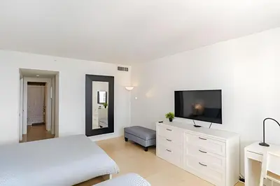 a white bedroom with a bed and a tv on a dresser at Pavilion -Amazing bay sunset-Miami Beach in Miami Beach