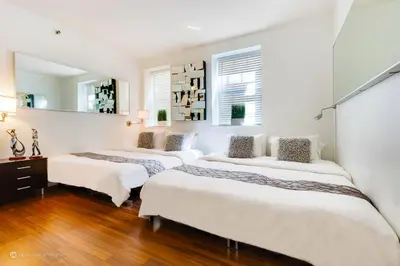 three beds in a room with white walls and wood floors at CasaGrandeSouthBeach by AmericanVacationLiving 4RM in Miami Beach