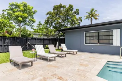 a patio with chairs and a swimming pool at Spacious 4 Bedroom 3 Bathroom House with Heated Pool and Outdoor Shower close to FFL Airport and Cruise Port in Plantation