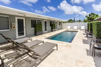 a swimming pool with chaises and chairs next to a house at Wiltonplex B in Fort Lauderdale