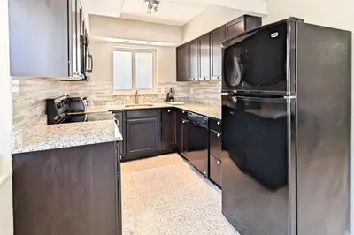 a kitchen with black cabinets and a black refrigerator at Wiltonplex C in Fort Lauderdale