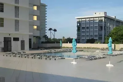 a pool with lounge chairs and blue umbrellas at Pavilion - Great ocean view -Miami Beach in Miami Beach