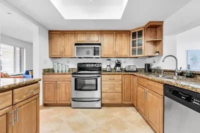 a kitchen with wooden cabinets and stainless steel appliances at Centrally Located 4BDR Pool Home in Miami in Miami Gardens