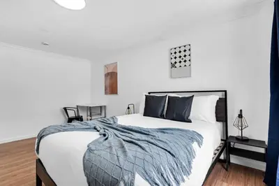a white bedroom with a large bed with a blue blanket at Centrally Located 4BDR Pool Home in Miami in Miami Gardens