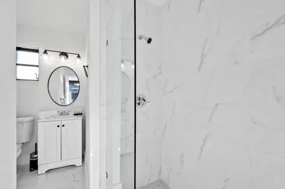 a white bathroom with a shower and a mirror at Modern Pool Home Great for Families in Hollywood