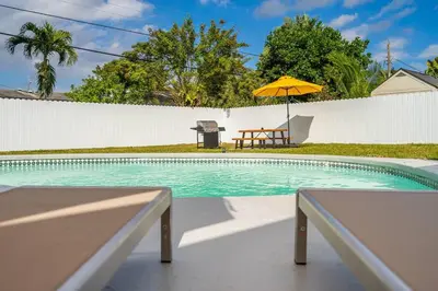 a swimming pool with a yellow umbrella and a bench at Modern Home 3 Bedrooms with Pool, 18 minutes to Ocean in Hollywood