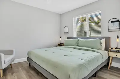 a white bedroom with a large bed and a chair at Sistrunk Shades Villas Units #1 & #2 Combined in Fort Lauderdale