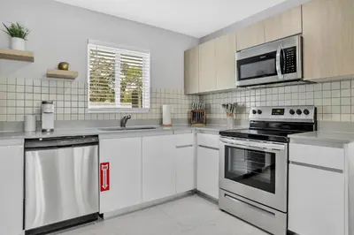 a kitchen with white cabinets and stainless steel appliances at Sistrunk Shades Villas Units #1 & #2 Combined in Fort Lauderdale