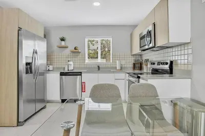 a kitchen with white cabinets and a stainless steel refrigerator at Sistrunk Shades Villas Units #1 & #2 Combined in Fort Lauderdale