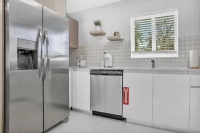 a kitchen with a stainless steel refrigerator and white cabinets at Sistrunk Shades Villas Units #1 & #2 Combined in Fort Lauderdale